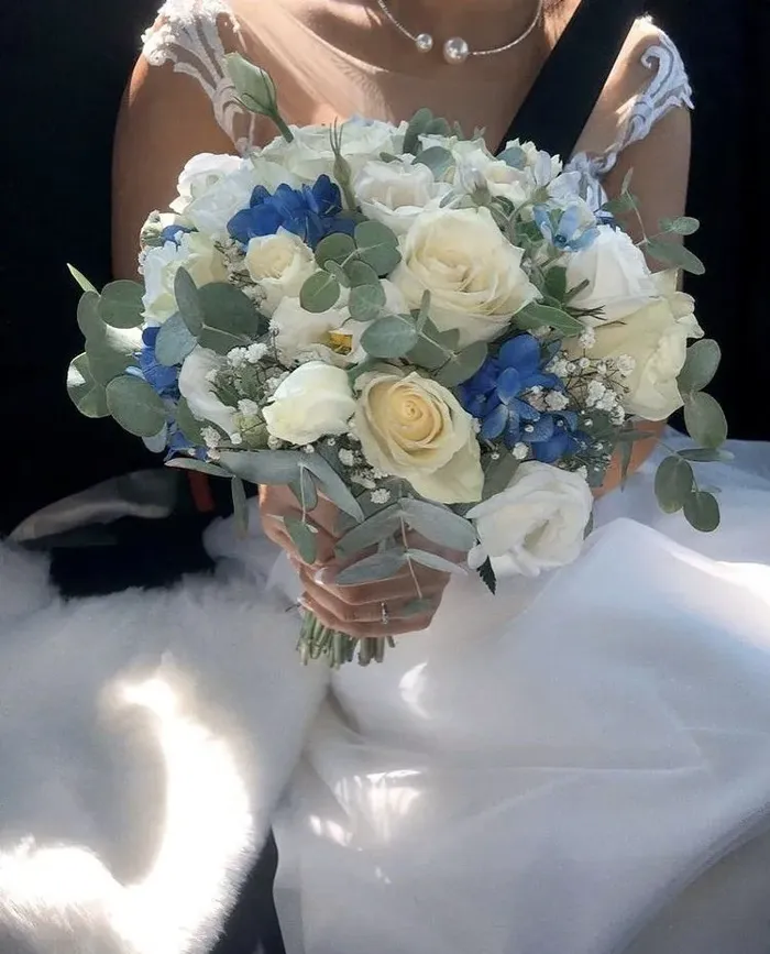Novia con un ramo de rosas blancas y flores azules